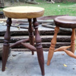 Two wooden benches, one dark brown with a light tan seat and the other a medium tan with a dark brown seat. Created by Thomas Ferrie.