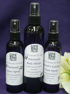 A bottle of patchouli body mister sits between two smaller bottles of linen spray, in Patchouli and Monet's Garden scents.