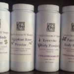 Four bottles of body powder. From left to right, jasmine, Egyptian rose, lavender, and patchouli from Carol's Scents N' Soaps.