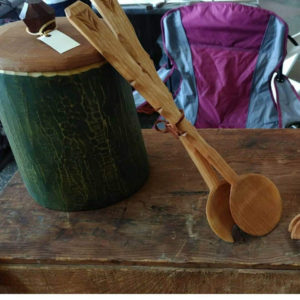 Long wooden tongs leaning against a green container by Vincent Pettit.