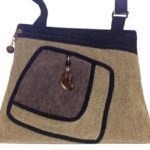 A tan purse with a black trim and strap, by Agustin Ruiz.