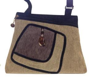 A tan purse with a black trim and strap, by Agustin Ruiz.