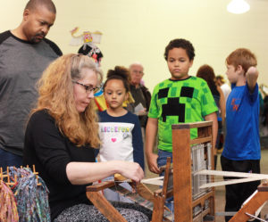Two children and an adult observing Amanda Robinette weaving Western Sakiori