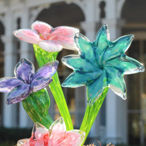 Three vibrant glass flowers, purple, pink, and teal.