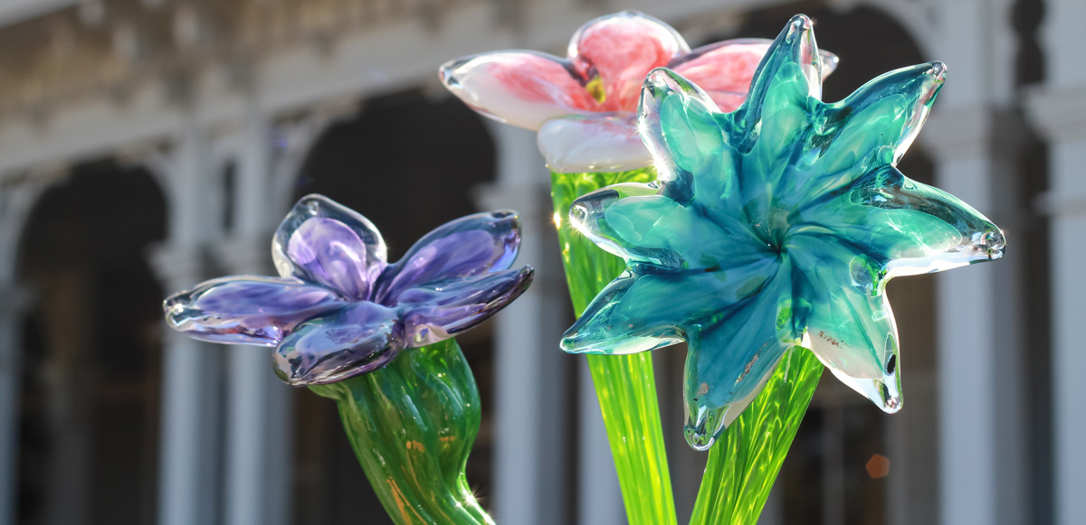 Three vibrant glass flowers, purple, pink, and teal.