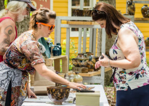 Artists selling a pottery to a customer outdoors at WheatonArts.