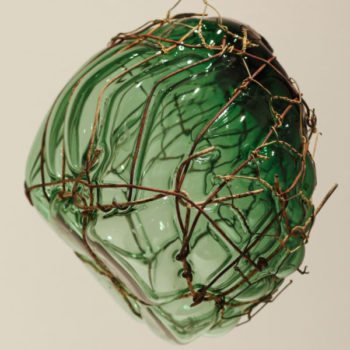 "Strange Roots" by Jesse Krimes, detail. A large piece of green translucent glass pushes out against a wire cage.