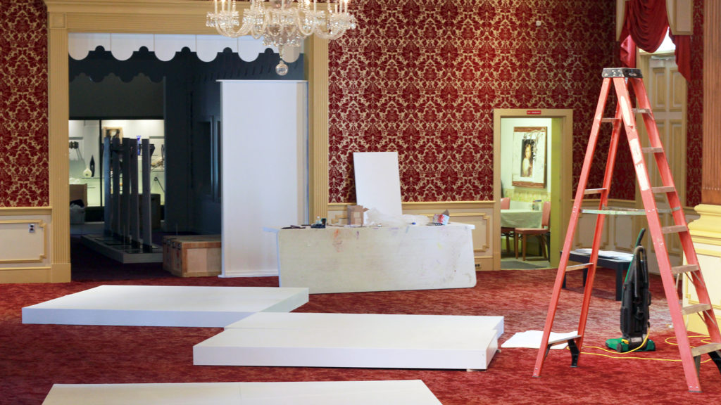 The Museum of American Glass lobby set up with platforms, a ladder, a vacuum, and a table with supplies.