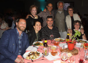 Men and woman gathered around a table during a benefit dinner.