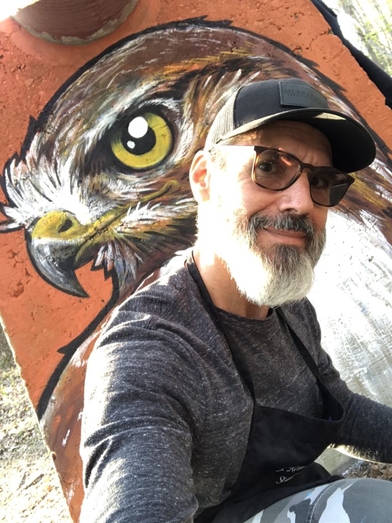 J. Kenneth Leap kneeling in front of eagle mural.