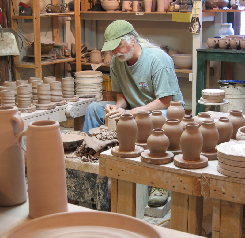 Terry Plasket working in the Pottery Studio surrounded by clay pots.