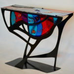 A glass table in red and blue by artist Sabra Richards.