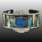 A turquoise colored cuff with a glittery blue stone in the middle. by artist Dolores Fawkes