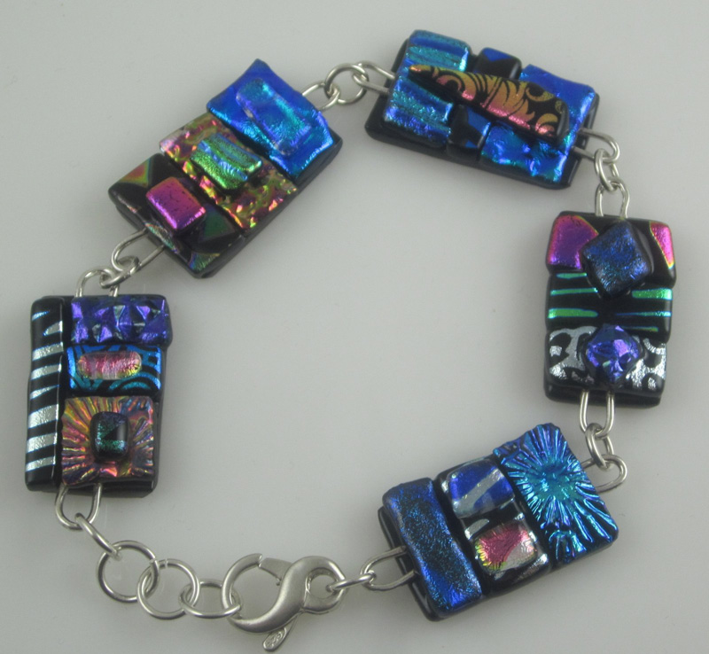 A bracelet by artist Pamela Iobst. A chain connects five rectangular, iridescent charms.