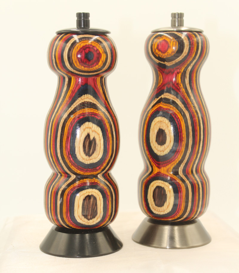 A pair of salt and pepper shakers by artist Larry Morgan. The matching wooden shakers have curves and concentric, colorful rings.