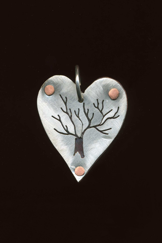 A pendant by artist Anthony Niglio. A silver heart pendant has a tree design and copper accents.