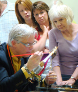 Shane Fero Demonstrating over a torch in Tazmania in front of three women.