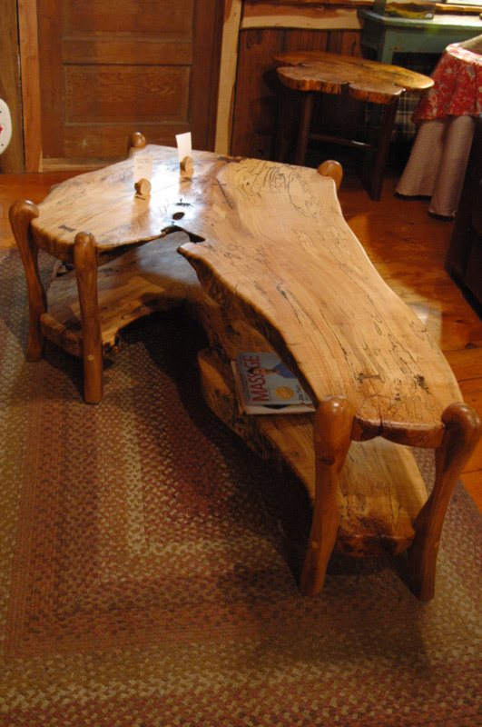 A long, shiny, naturally shaped wooden table, made by artist Abe Warren.
