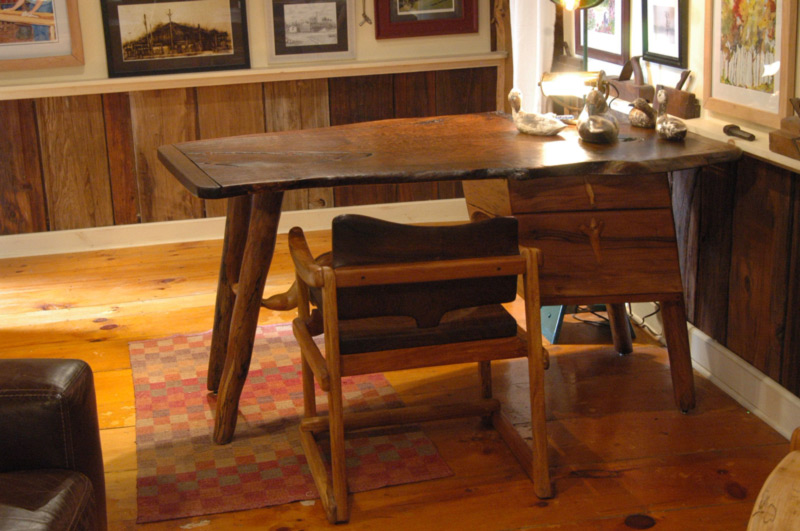 A wooden chair is tucked beneath a desk, made by artist Abe Warren.