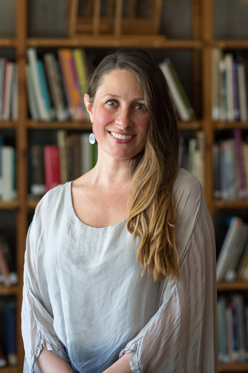 Headshot of Charlotte Potter, smiling in front of a bookshelf.