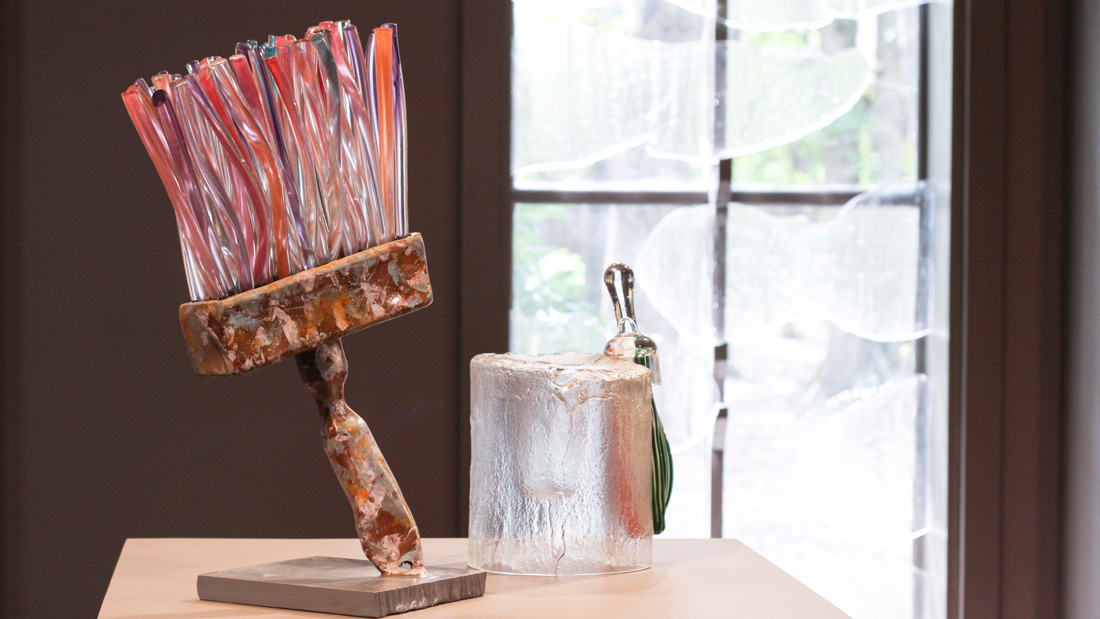 A large glass paintbrush with pink and red bristles is displayed in the Museum of American Glass.