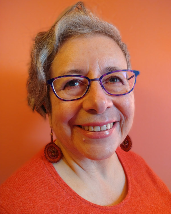 Headshot of Yolanda Alcorta in an orange outfit, smiling wide.