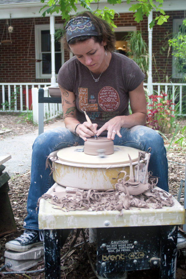 Clay Studio Artist Erica Pugh works on a potters wheel, outdoors on a sunny day in front of the Pottery Studio.