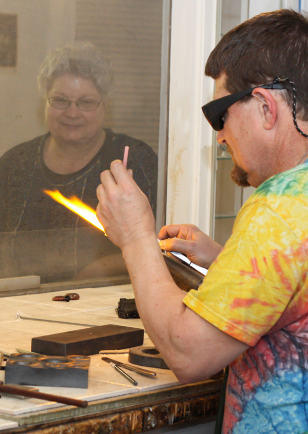 Flameworking Artist Bill Futer shapes a piece of pink glass cane over a torch in the Flamework Studio.