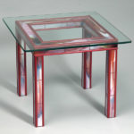 A red square table with a clear glass top by Antonio Loria.