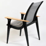 A black wooden chair with a gray cushion and tan wooden handles, by William Robbins.