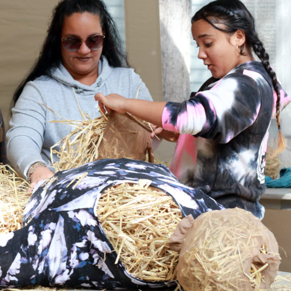 An adult and child work together to build a scarecrow at the Festival of Fine Craft.