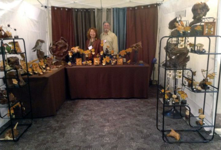 David & Barbara Shields stand behind a booth showing their work.