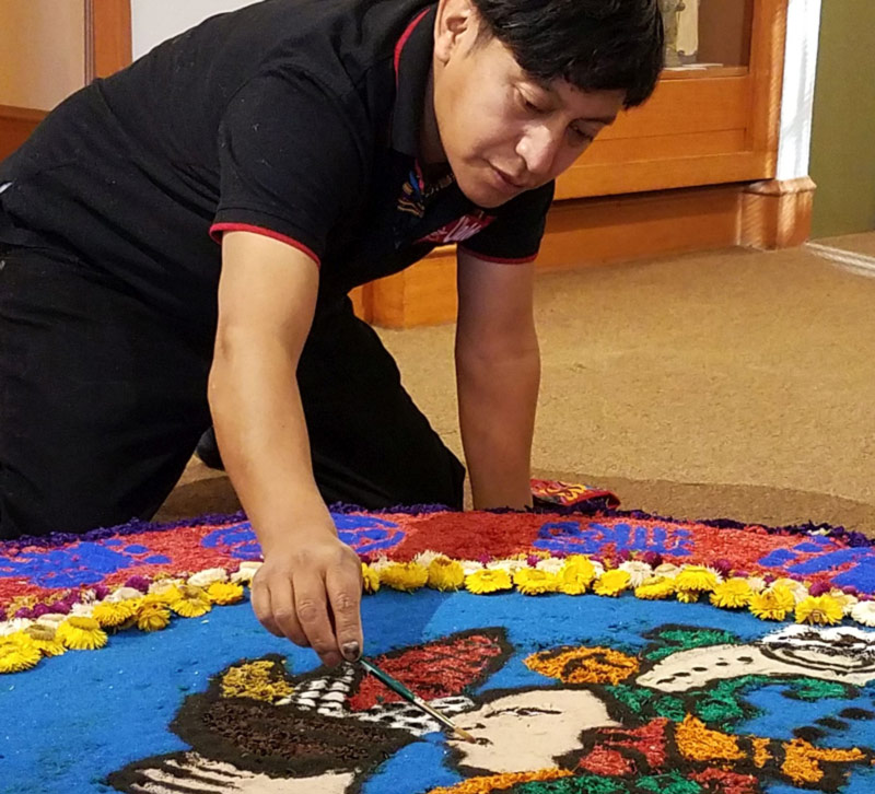 Ubaldo Sanchez carefully places sawdust onto an intricate sawdust carpet.