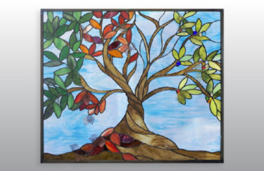 A stained glass panel by Jill Tarabar with a tree in different stages of seasons.