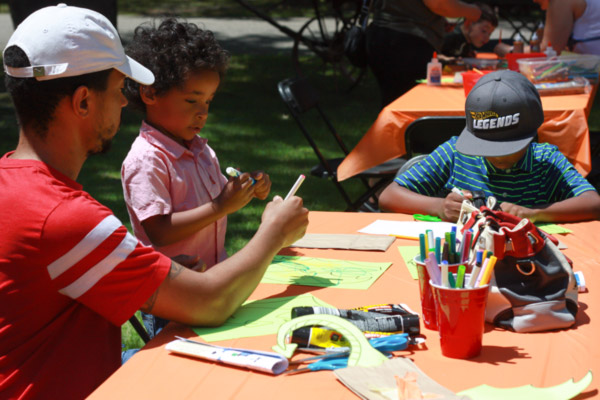 Fantasy Faire 2019 attendees participate in kids' craft activities with adult supervision outdoors.