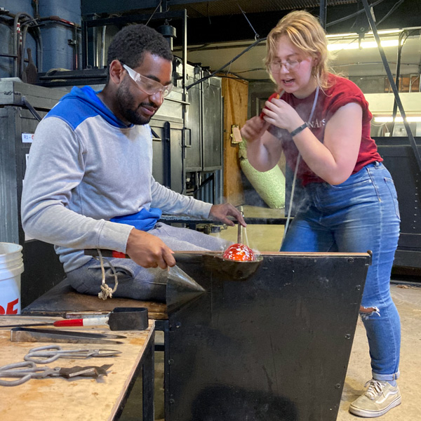 A Studio Assistant assists a WheatonArts guest during a Make-Your-Own experience.