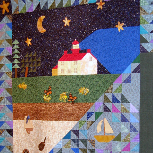 A fabric cultural piece used as advertisement for the WheatonArts folk art instruction program. The fabric is a large rectangle with a multicolored border. The border has squares with a variety of colored triangles At each corner is a square with an orange star. The bottom right of the fabric has a multicolored triangle with a sail boat in the middle of it. This triangle goes to about halfway through the piece. The rest of the space is filled with a picture of soil, dirt, grass, a house with trees next to it, and stars with a moon above it. The house has a lighthouse on top of its red roof and is shining a blue light to the right of it. There are also butterflies and other insects by the ground.