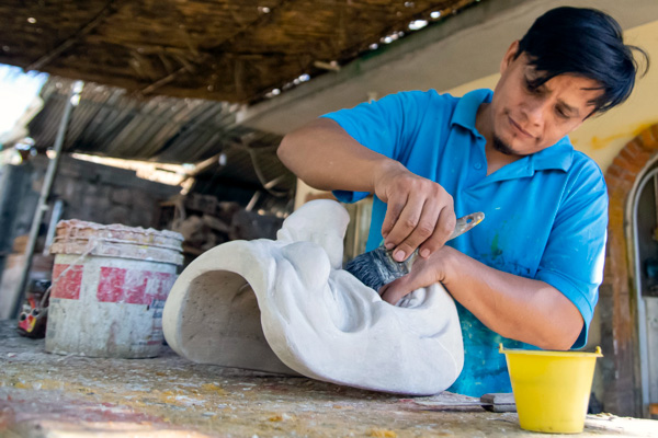 HalloWheaton: Remembering Your Ancestors Celebration Special Program artist Rafael Jimenez Lopez is wearing a blue polor shirt and painting a clay mask for the celebration.