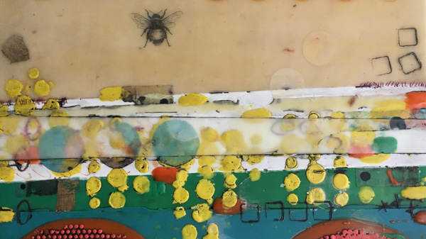 An encaustic painting by workshop instructor Sandra Koberlein with a design of a bee at the top over a beige portion is the subject of the image. There are several stripes of white & green with several small dots of yellow & large dots of blue below the beige portion.