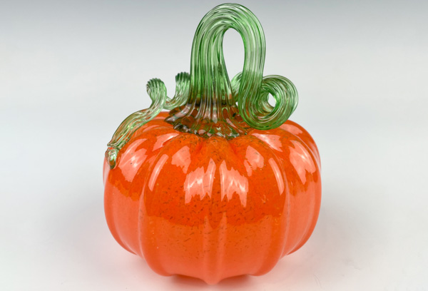 An orange glass pumpkin with a light green stem is used to promote the glass pumpkin make-your-own experience.