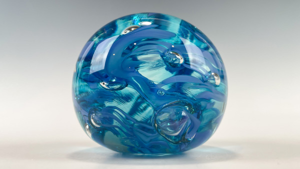 A blue paperweight with a swirl pattern on it's surface is used to promote the swirl paperweight make-your-own experience.