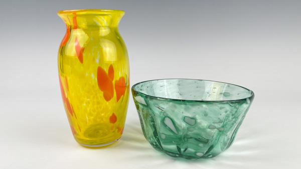 A light blue glass bowl is to the right of a yellow, orange spotted vase. Both are possible creations in the bowl/vase make-your-own experience.