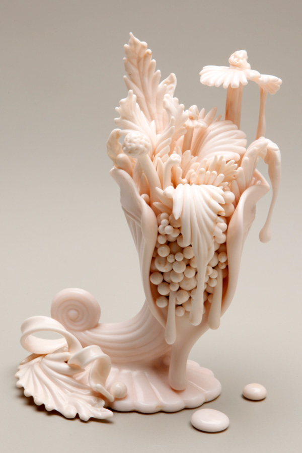 A white-pink sculpture by the Alchemy of Adornment exhibit artist Amber Cowen shows floral and fauna dripping and growing over a plant.