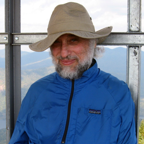 This image is a close-up of Gerardo Razumney, wearing a blue zippered up windbreaker and smiling at the camera.