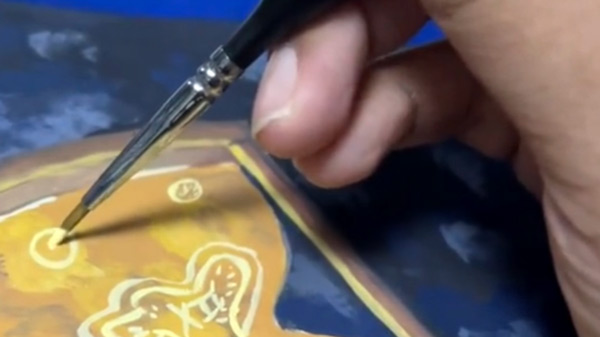 A detail of an artist painting an example of the introduction to conceptual painting workshop with instructor Sumayyah Hayes is of an hourglass over a dark blue background.