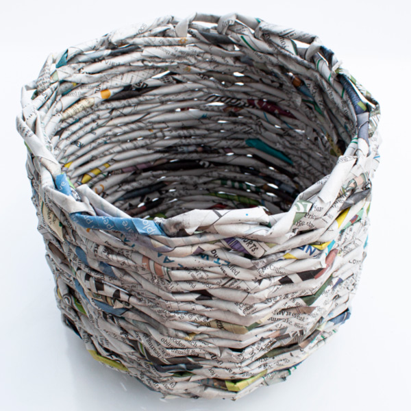 Image of a basket that was woven with newspaper against a white background.