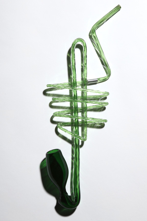Image of a dark green glass pipe from the Centuries of Tomfoolery exhibit in front of a white background. The pipe is comprised of a long tube that wraps around itself four times before looping up then down into the pipe shape.