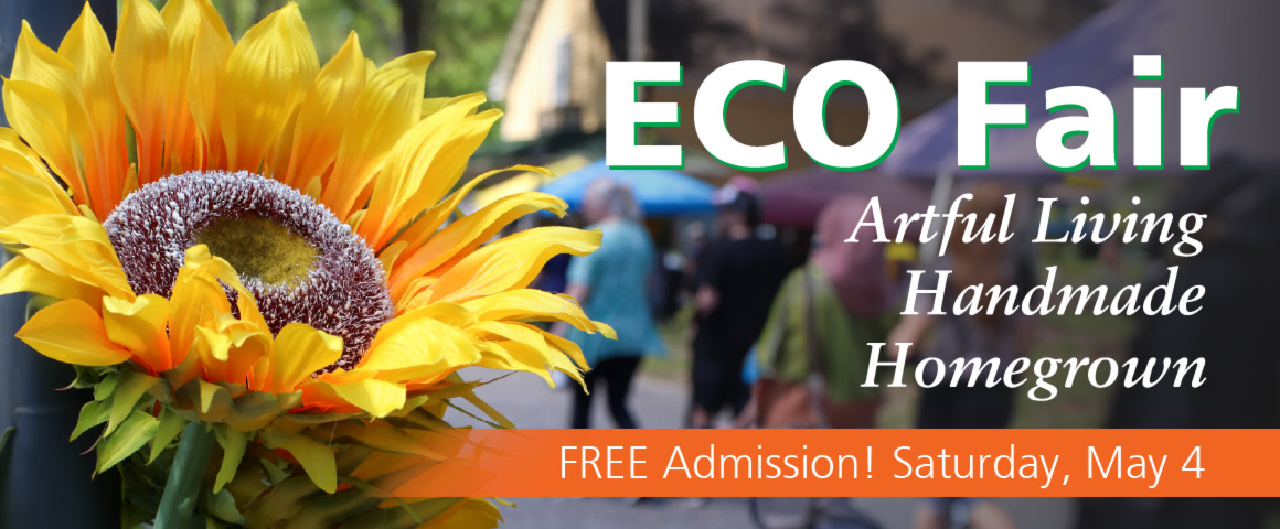 Image of the banner for Eco Fair. On the left side of the image is a large close-up of the head of a yellow sunflower. On the right side of the banner is large white text with a green drop shadow that reads "Eco Fair". Underneath is white text that reads "Artful Living", "Handmade", and "Homegrown". Below that is an orange rectangle that fades in opacity as it reaches the sunflower. Inside of the rectangle is white text that reads "Free Admission! Saturday, May 4". In the background, on the right side of the image, is a blurred image of a crowd outside at WheatonArts in front of the General Store during Eco Fair.