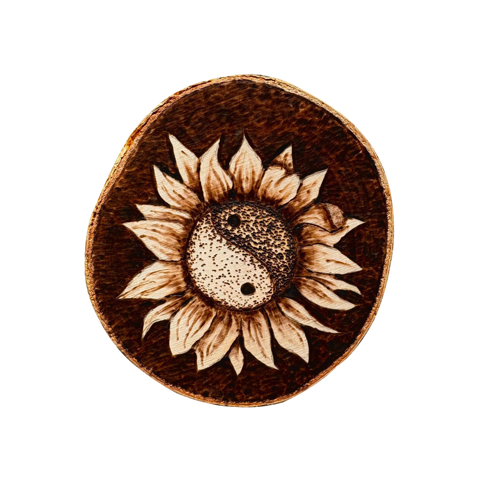 Image of a circular, dark brown piece of wood with a sunflower design burnt into the center. The center of the flower is the Yin-Yang symbol.
